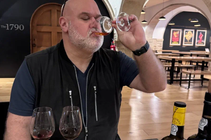 Matt nosing a glass of port at Sandeman, “The 1790” arch and stone vaults visible behind him