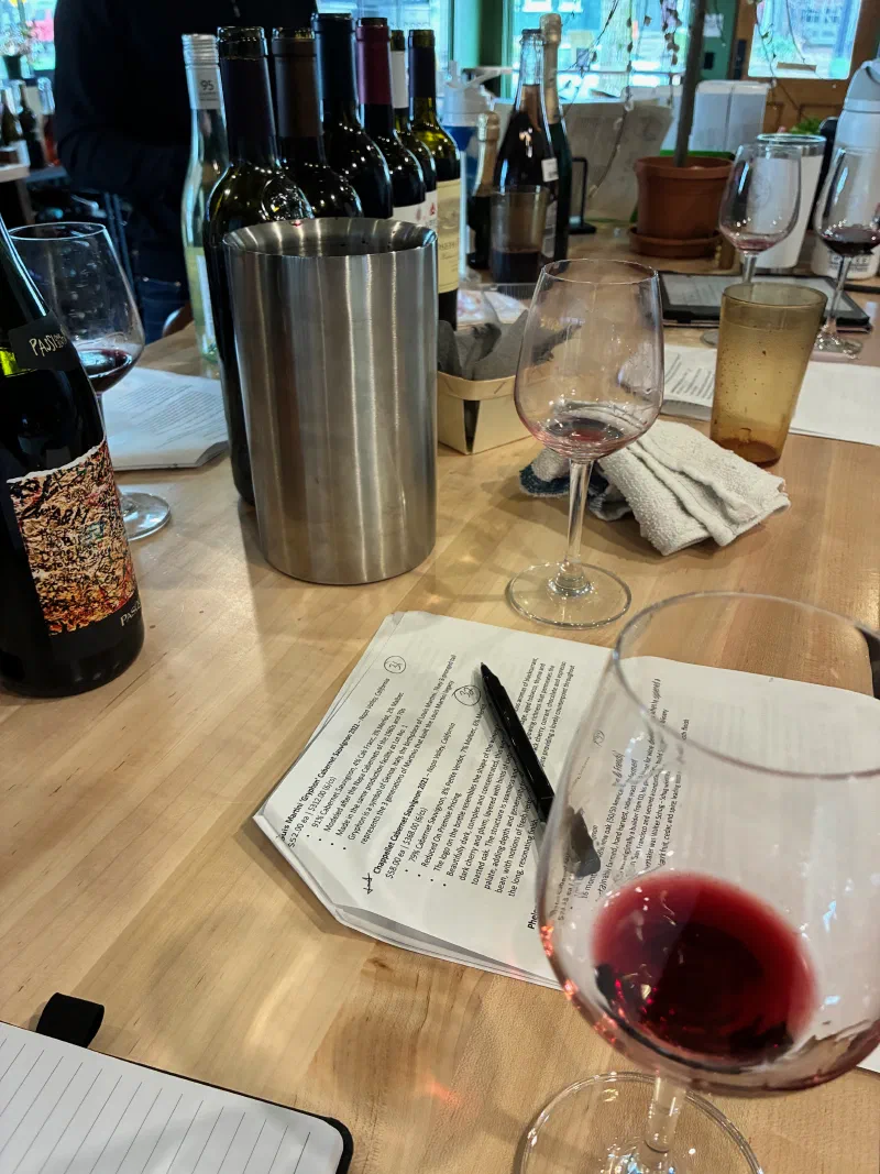 Tasting room counter — bottles, wine glasses, and a printed tasting guide with notes